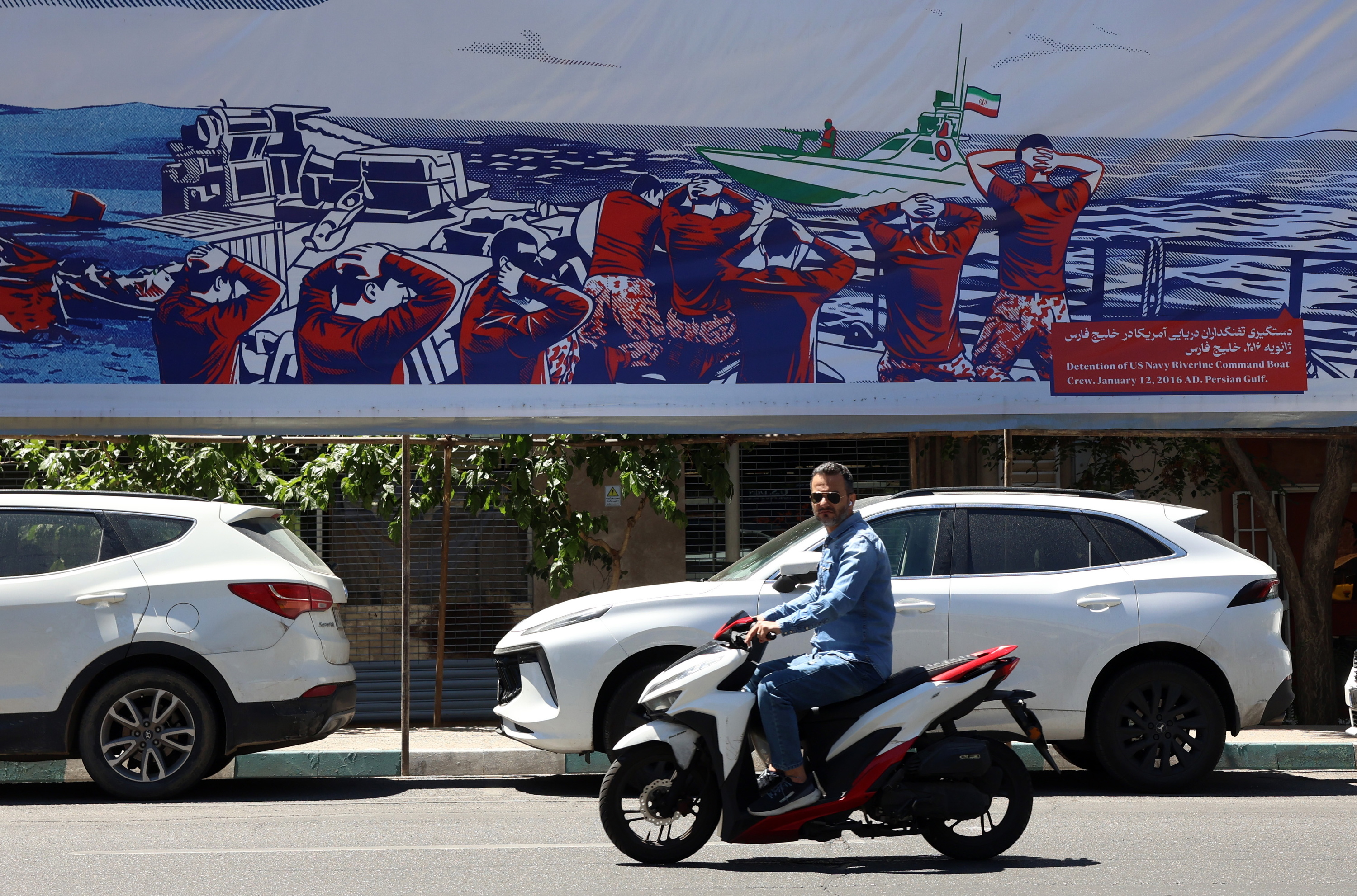 Motorzale bat asteartean, Teheranen egin duten kartel baten ondoan. ABEDIN TAHERKENAREH / EFE