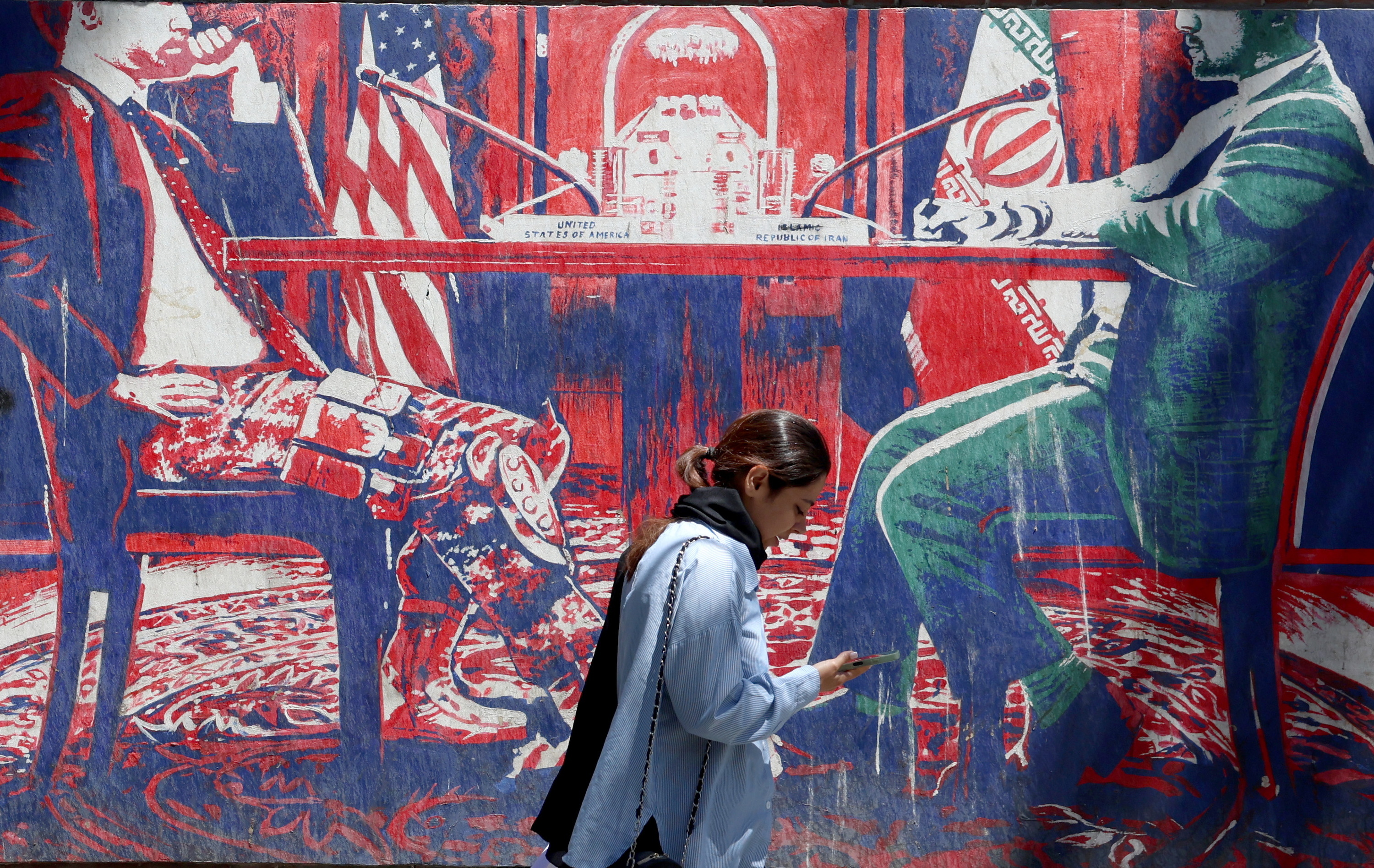 Emakume bat Teheranen, ondoan Iranen eta AEBen arteko negoziazioak irudikatzeko mural bat duela, maiatzean. ABEDIN TAHERKENAREH / EFE
