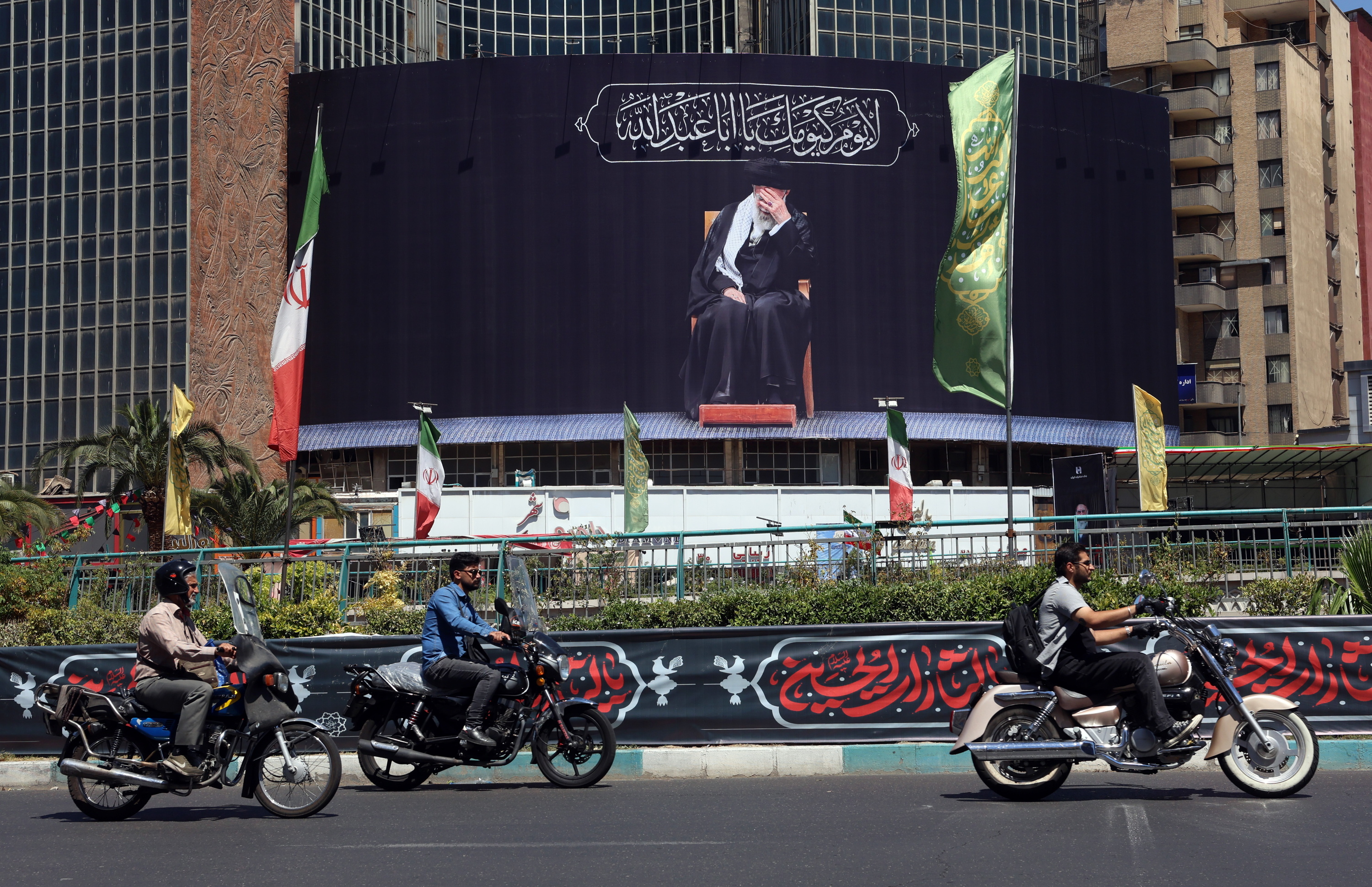 Motozale batzuk gaur Teheranen, Ali Khameneiren omenezko mural baten aurretik igarotzen. ABEDIN TAHERKENAREH / EFE