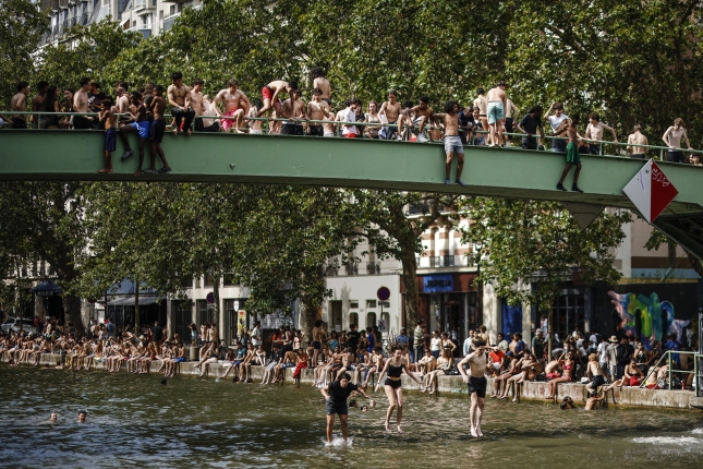 Dozenaka herritar bainua hartzen Parisko kanal baten, larunbatean. YOAN VALAT / EFE