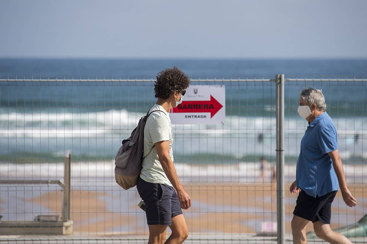 Bi lagun maskara jantzita paseoan, Zarauzko hondartzan. GORKA RUBIO/FOKU