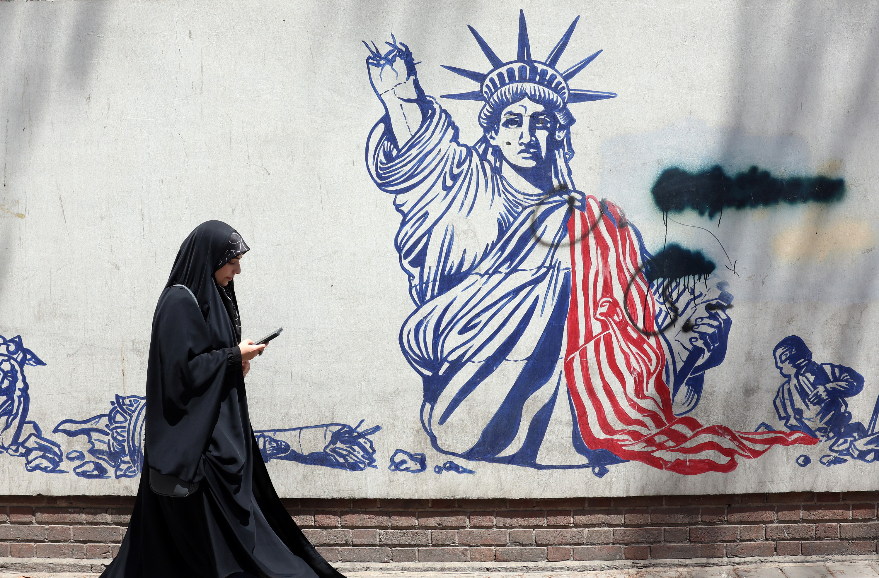 Emakume bat AEBen aurkako mural baten aurretik igarotzen, Teheranen. ABEDIN TAHERKENAREH/EFE