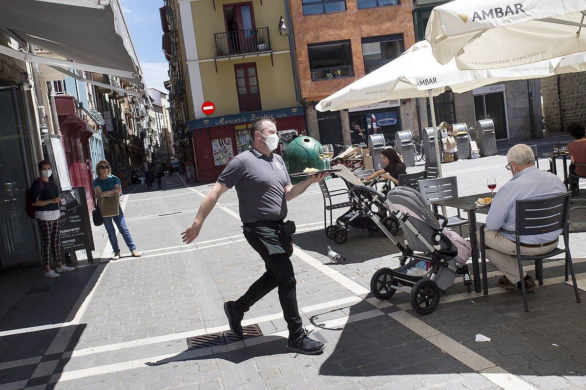 Zerbitzari bat Alde Zaharreko terraza batean zerbitzatzen, ekainean. Ostalaritzan kontratazioek nabarmen egin dute behera bigarren hiruhilekoan. IñIGO URIZ / FOKU