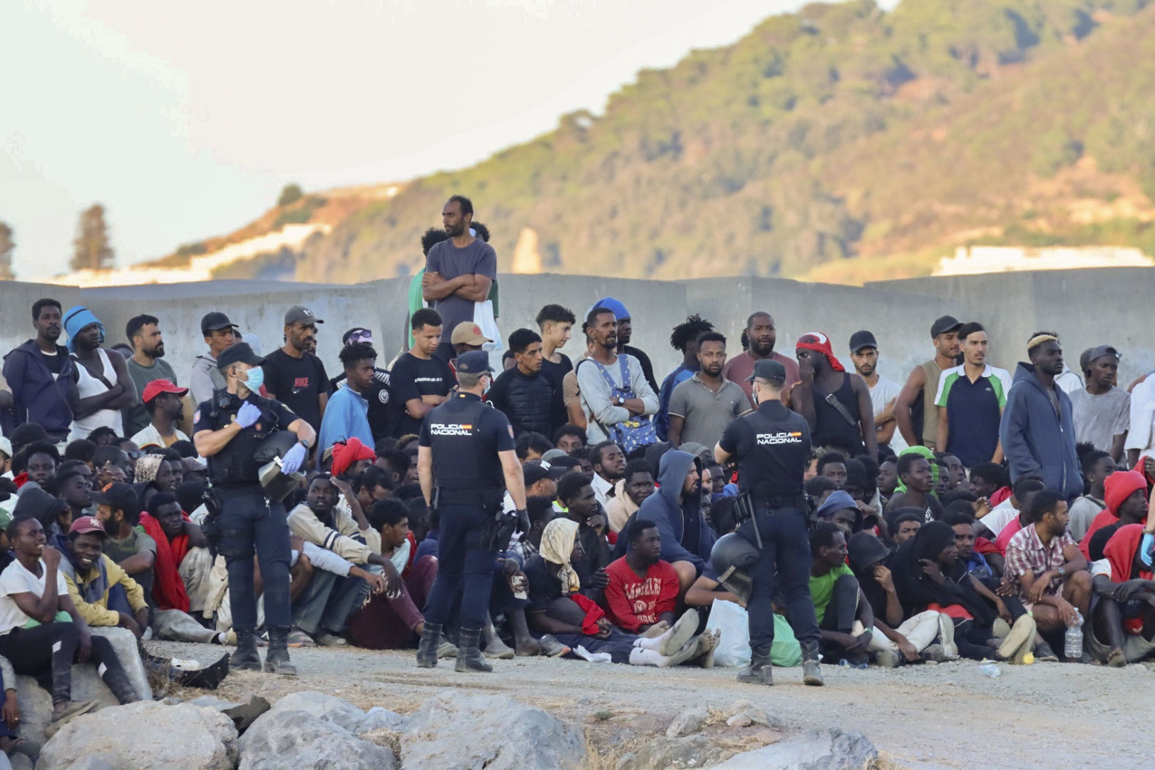 Dozenaka migrante Espainiako Poliziak inguratuta, atzo, Ceutako El Trampolin hondartzan. REDUAN / EFE
