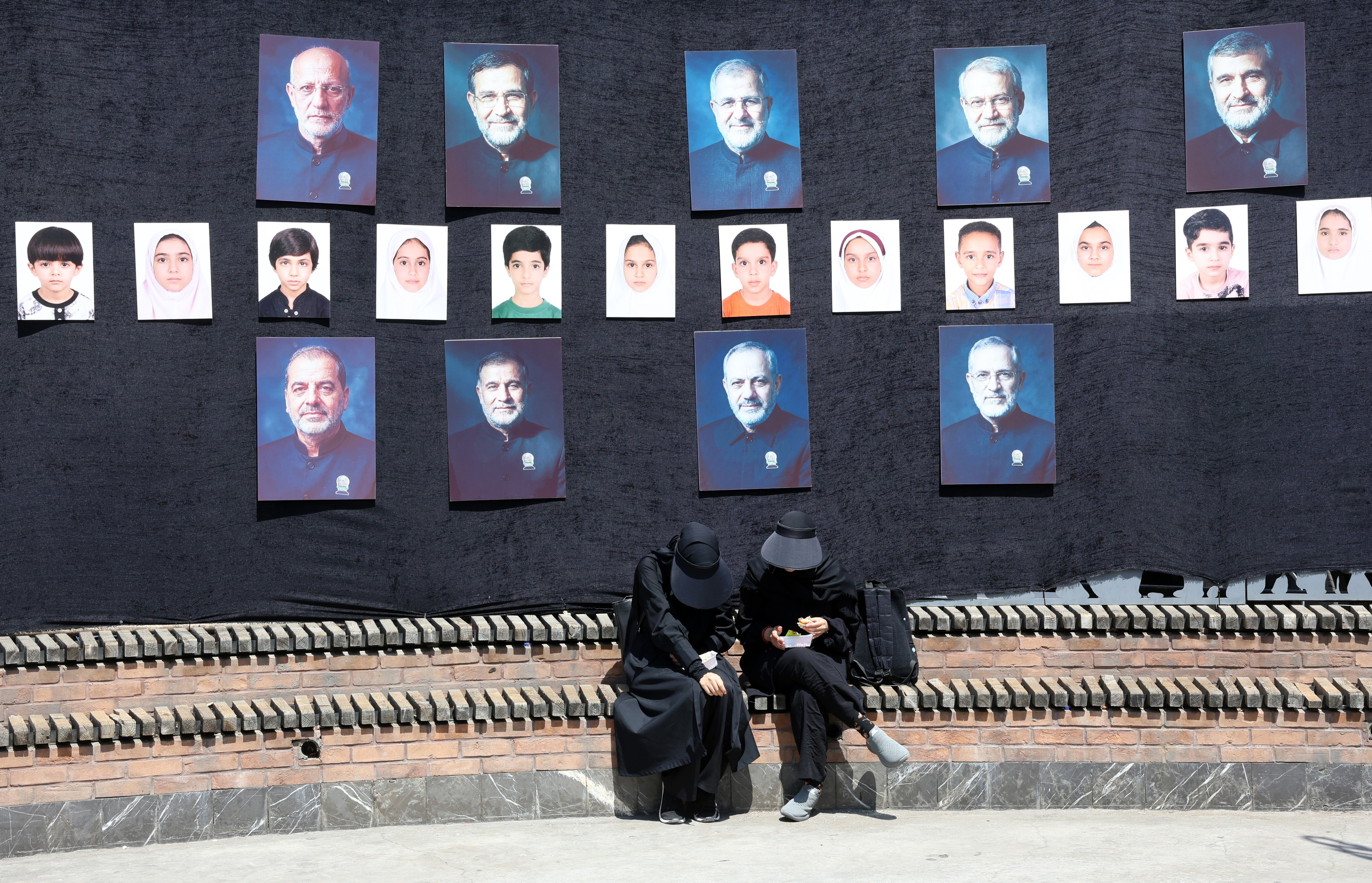 Bi emakume Teheranen, atzo, atzean Irango liderren eta AEBek Iranen hildako haurren irudiak dituztela. ABEDIN TAHERKENAREH / EFE
