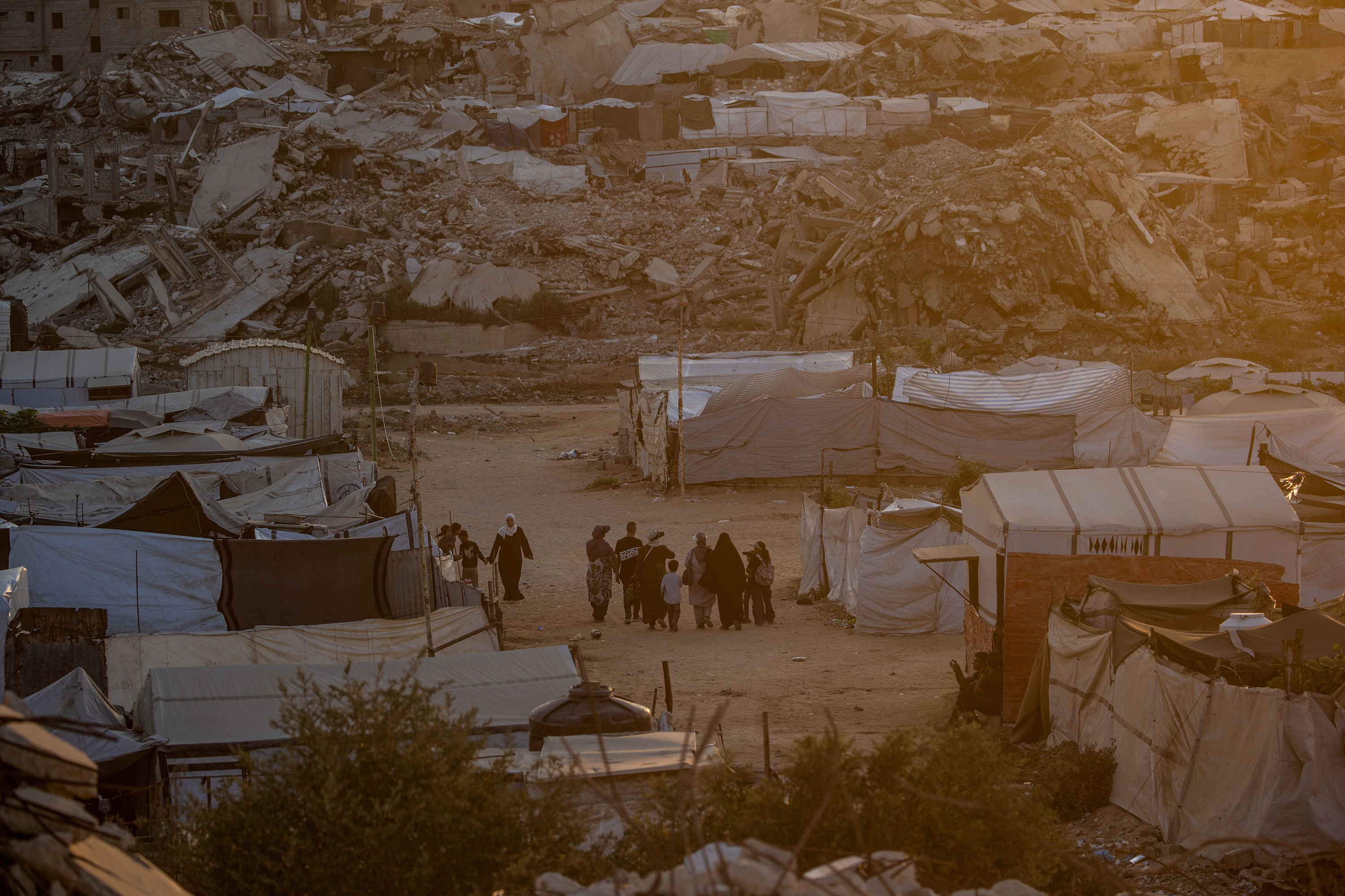 Palestinar batzuk Israelek suntsitutako eraikin batzuen inguruan, Gaza hirian, larunbatean. MOHAMMED SABER / EFE