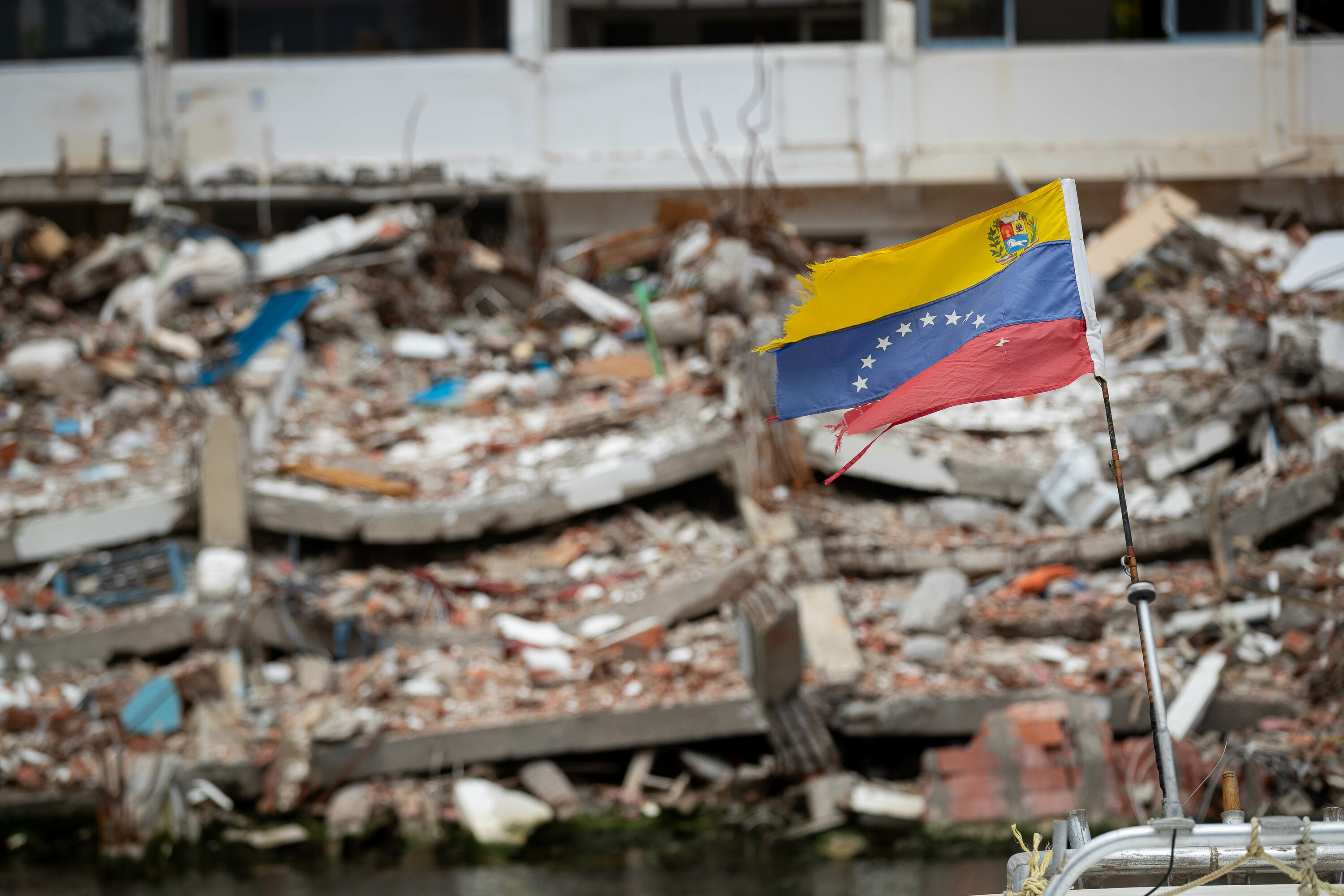Venezuelako bandera bat asteburuan La Guaira hirian, atzean ekaineko lurrikaretan eroritako eraikin baten hondakinak dituela. RONALD PEÑA / EFE