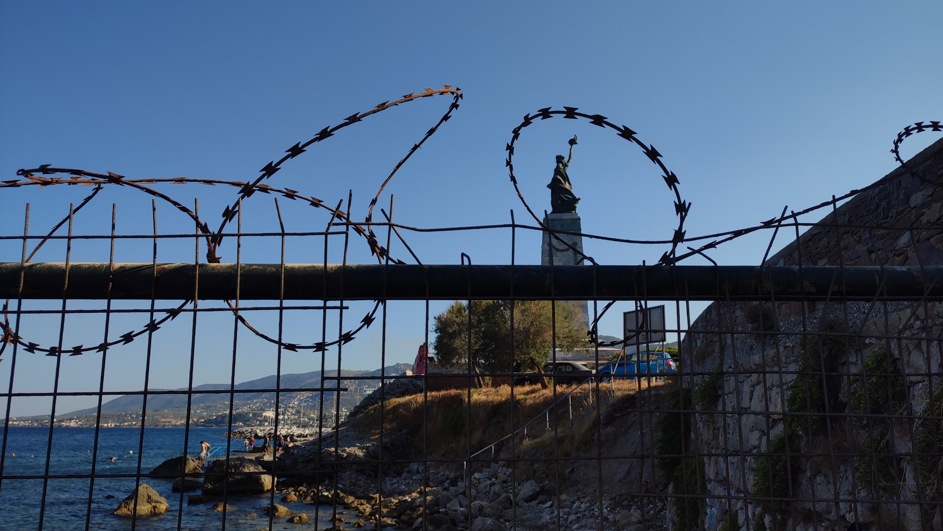 Mitileneko hondartza eta plataforma bereizten dituen hesia, atzean Askatasunaren estatua dagoela. MADDI ITURRIOTZ ALKORTA