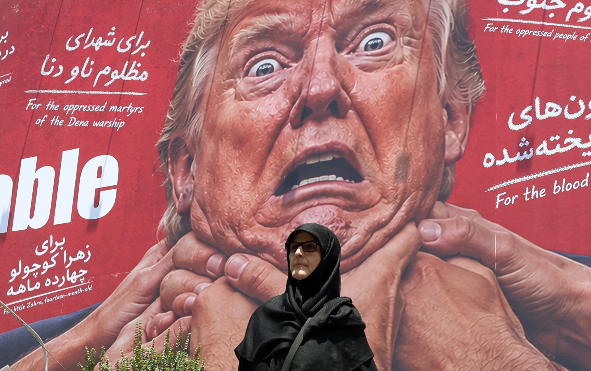 Emakume bat Teheranen, uztailean, Donald Trumpen irudi bat atzean duela, hainbat esku lepoa bihurritzen ari zaizkiola. ABEDIN TAHERKENAREH / EFE