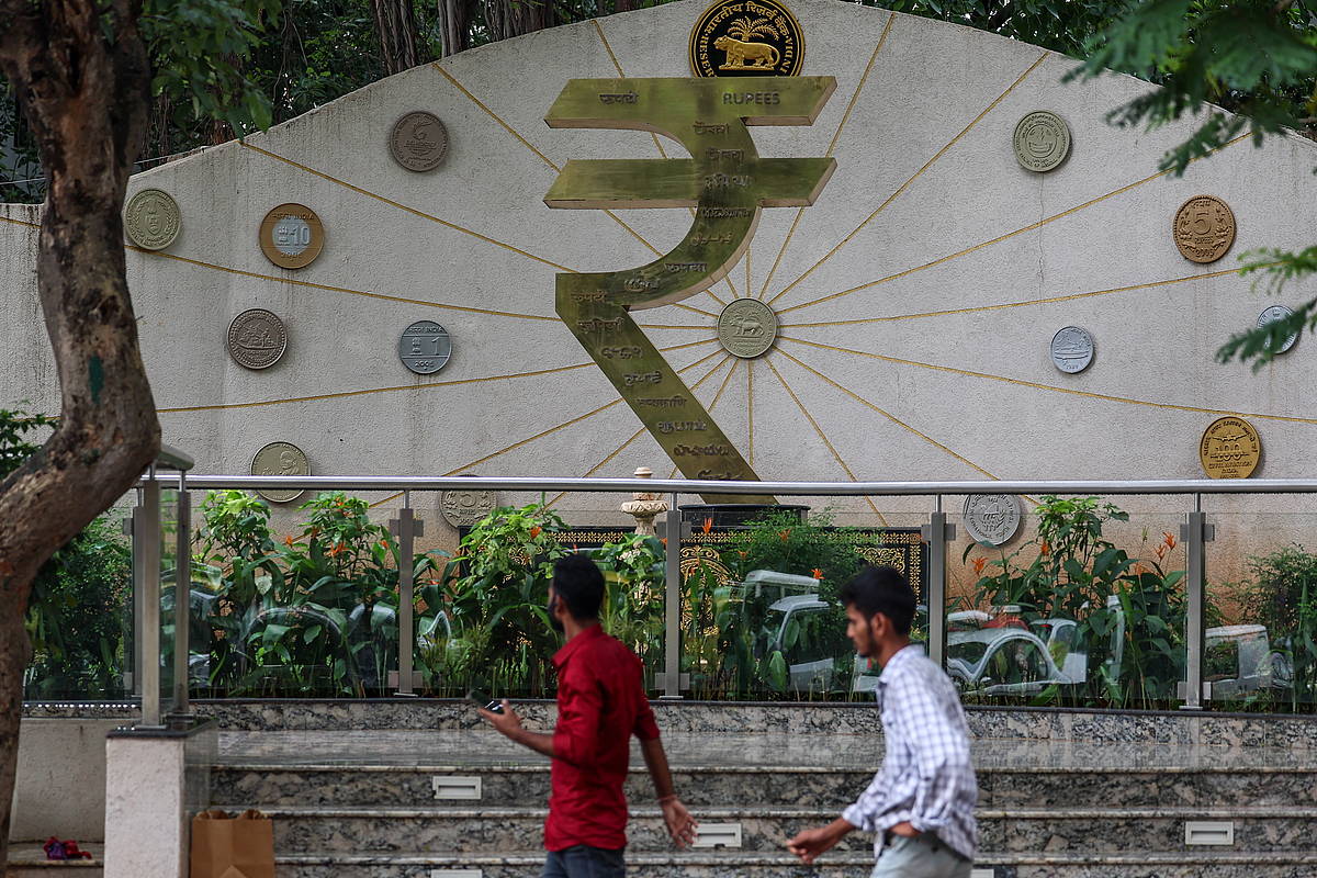 Jendea Indiako errupiaren ikurraren ondotik pasatzen, Indiako Erreserba Bankuaren egoitzaren ondoan, Mumbain. DIVYAKANT SOLANKI / EFE