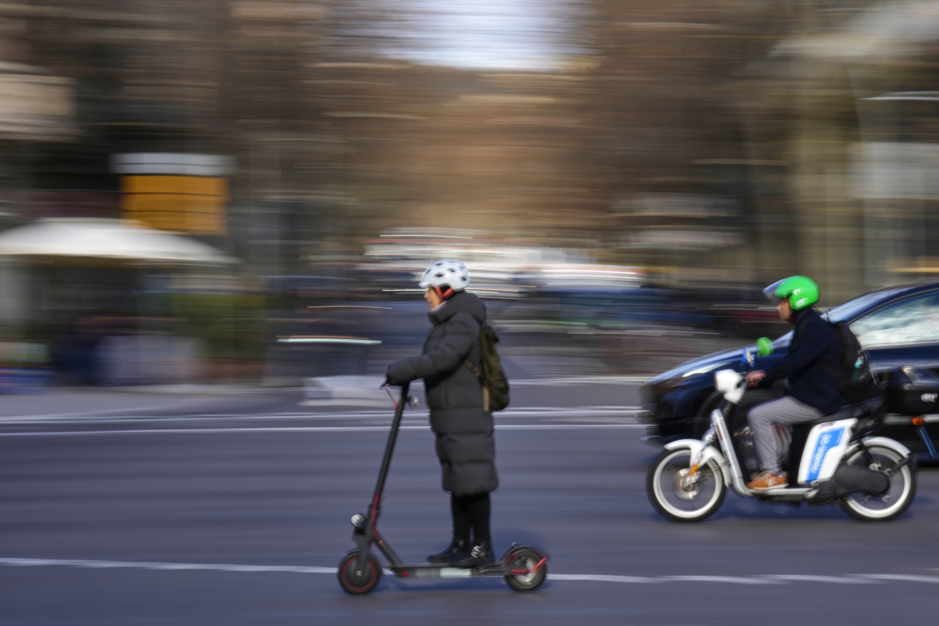 Emakume bat patinete elektrikoan, kaskoa jantzita, eta gizon bat motoan, artxiboko irudi batean. ALEJANDRO GARCIA / EFE