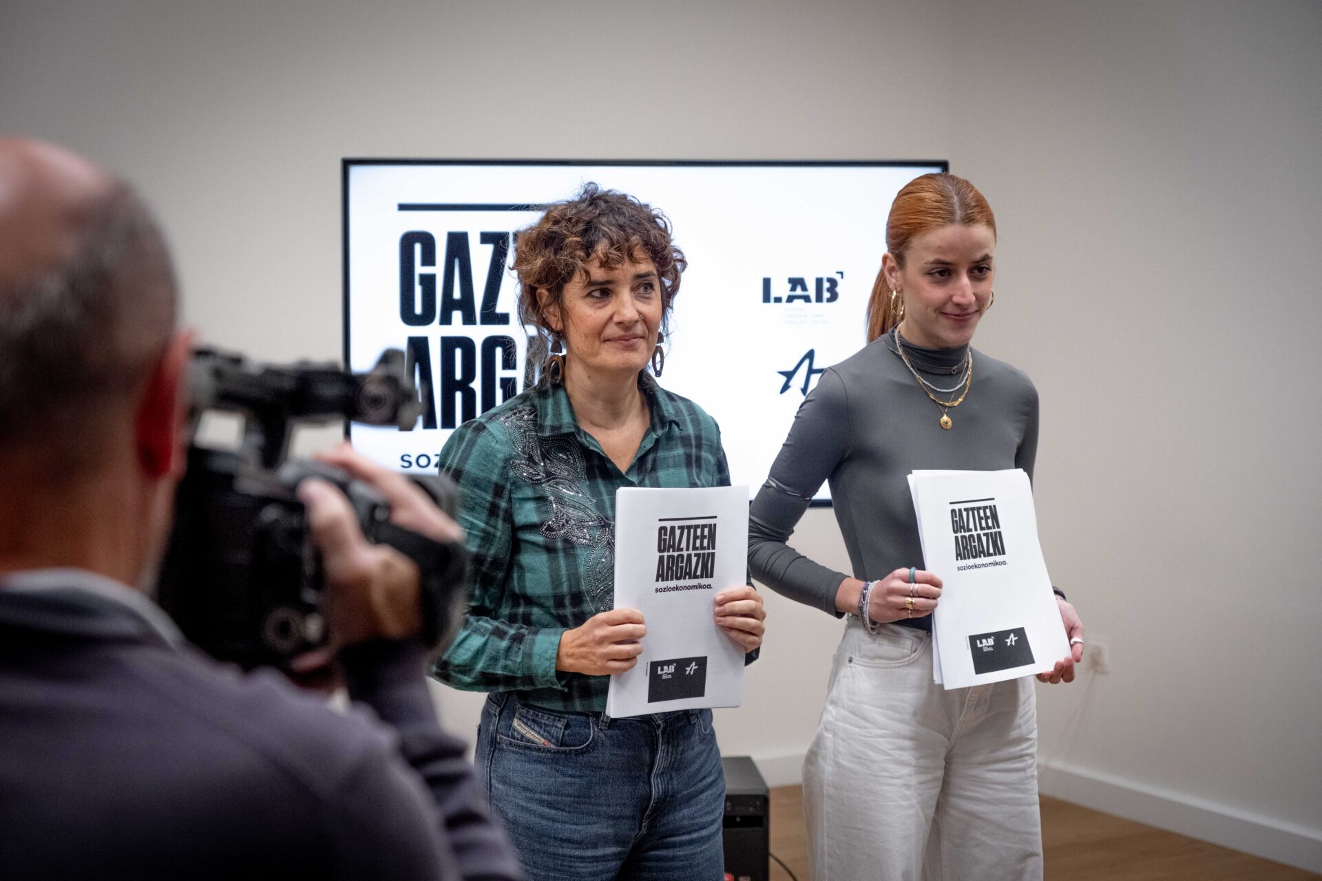 Oihana Lopetegi LAB sindikatuko ekintza sindikaleko ordezkaria eta Amaia Arbeo Ernai gazte antolakundeko bozeramailea, txostenarekin. LAB
